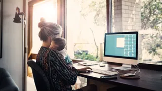 Ouder met kind op schouder achter computer